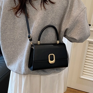 Chic black leather handbag with gold oval lock and shoulder strap for elegant women