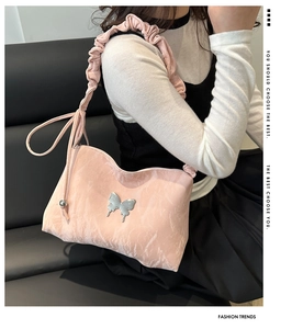 Gros plan du sac à bandoulière rose avec boucle papillon et détail de sangle froncée