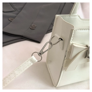 Detail of silver metal lobster clasp and PU leather strap on a minimalist white handbag