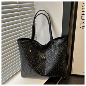 Detail of black woven leather tote bag with elegant gold studs and minimalist handle
