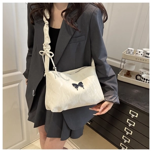 Détail du sac fourre-tout crème avec fermoir papillon noir et bandoulière froncée stylée