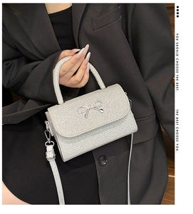 Close-up of silver glitter crossbody bag with metallic bow detail and top handle