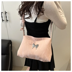 Détail du sac cabas rose nacré avec texture plissée et ornement papillon argenté