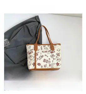 Detailed view of the off-white tote bag featuring cartoon prints and brown shoulder straps