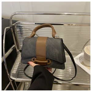 Detail of vintage crossbody bag with brown leather handles on a minimalist display