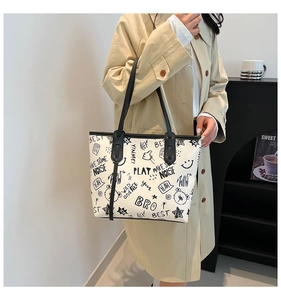 Detail of graffiti-style print tote bag with black shoulder straps on model's shoulder