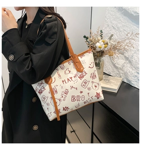Close-up of white tote bag with cartoon graffiti prints and brown leather handles
