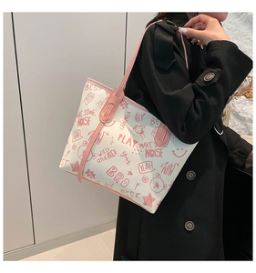 Side view of white graffiti tote bag with pink straps worn over a long black coat