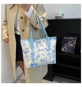 Detail view of large tote bag featuring blue street graffiti print and slim shoulder straps