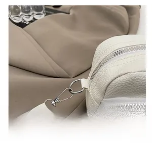 Detailaufnahme einer weißen Tasche mit Litchi-Muster, Metallhaken und Doppel-Reißverschluss