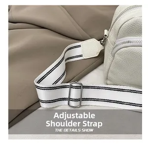 Detail der weißen Handtasche mit Lederprägung und verstellbarem Streifen-Schultergurt