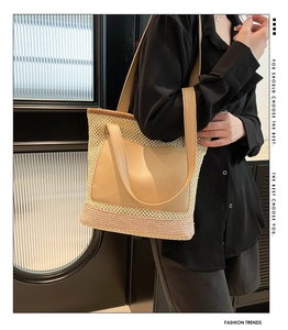 Close-up of woven straw tote bag featuring leather pocket and dual-color拼接 design