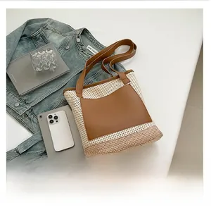 Flat lay of woven beach tote featuring brown leather pocket and dual shoulder straps