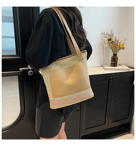 Detail of woven straw tote bag featuring a leather pocket and shoulder straps for women