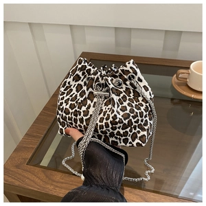 Leopard print drawstring bucket bag with silver chain strap shown in a lifestyle setting