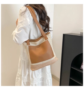 Detail of woven straw tote bag with brown leather pocket and adjustable shoulder strap