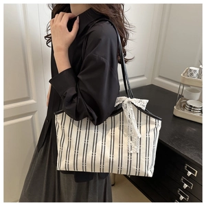 Detail of striped canvas tote bag featuring a large white lace bow for a sweet style