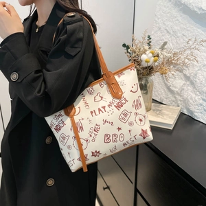 Large capacity tote bag with artistic graffiti prints and brown leather handles on a model