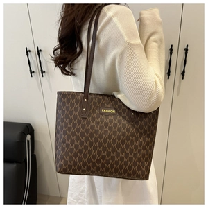 Détail du sac cabas marron avec motif monogramme M et plaque logo en métal