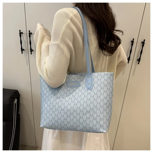 Detail view of light blue tote bag featuring M monogram pattern and FASHION leather tag