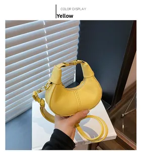 Detail view of yellow crescent hobo bag with gold metal buckle and contrast stitching