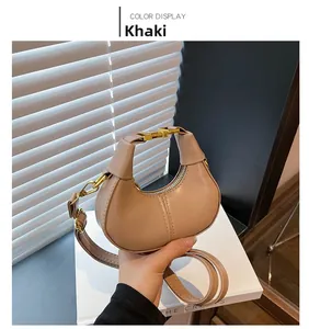 Detail of khaki PU leather crescent bag with gold hardware and strap in soft shadows