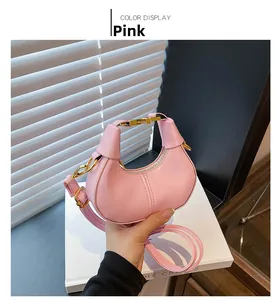 Detail of pink half-moon crossbody bag featuring gold buckle and thin leather strap