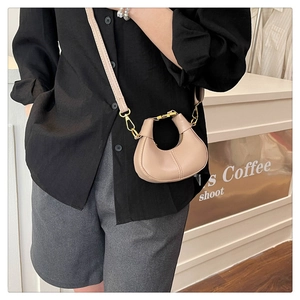 Detail of minimalist crescent handbag with detachable leather strap and gold hardware