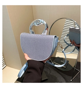Detail of light blue saddle bag with textured fabric and shiny silver metal handle