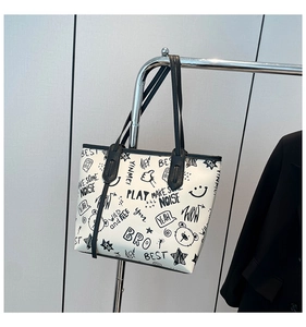 Détail d'un grand sac cabas avec imprimés graffiti artistiques et bandoulières en cuir PU noir