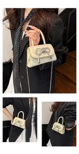 Détail du mini sac crème avec un nœud en strass et une bandoulière en chaîne argentée