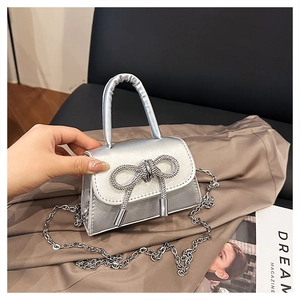 Détail du mini sac carré argenté avec nœud en strass et bandoulière en chaîne