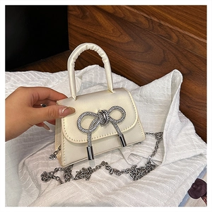 Détail du mini sac en satin montrant le nœud en strass brillant et la bandoulière