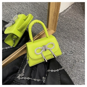 Gros plan du mini sac vert citron avec un nœud en strass et une bandoulière chaîne