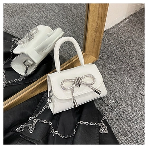 Gros plan détaillé d'un sac en cuir blanc orné d'un grand nœud en strass argentés brillants