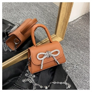 Détail d'un mini sac à main marron avec nœud en strass argentés et bandoulière chaîne