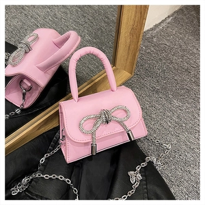 Détail du mini sac à main rose avec nœud strass brillant et bandoulière chaîne
