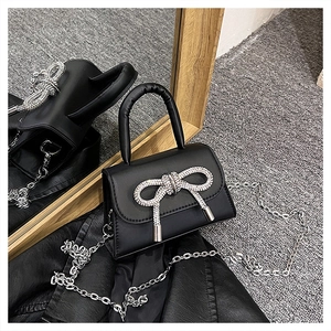 Détail du mini sac noir avec nœud en strass et bandoulière en chaîne argentée