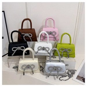 Dettaglio di mini borse con fiocco in sette colori con tracolle a catena sottile