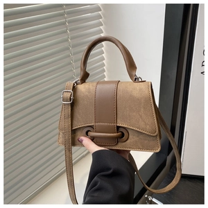 Detail view of khaki brown canvas handbag with dark leather strap and buckle closure