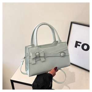 Detail of mint green handbag featuring matching bow and premium adjustable metal buckle