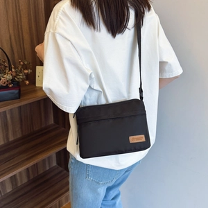 Borsa a tracolla nera minimalista in nylon con doppia cerniera e tracolla regolabile