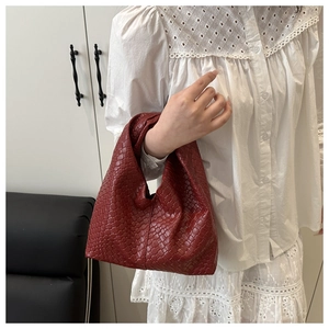 Detailed view of the red woven leather tote bag texture held by a model in lace shirt