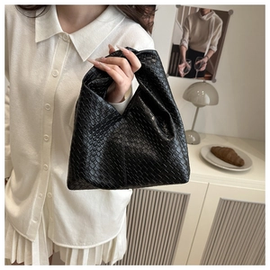 Close-up of black woven leather tote bag with classic Intrecciato pattern and single handle