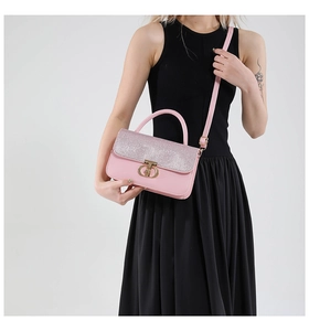 Detailed close-up of pink luxury handbag featuring sparkling sequins and gold T-lock closure