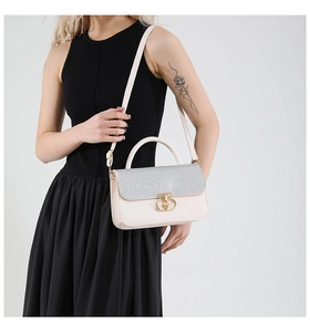 Detailed look at beige crossbody bag with silver sequin flap and gold buckle on a model