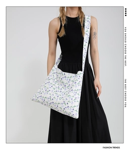 Close-up of white canvas tote bag featuring purple floral patterns and wide shoulder strap