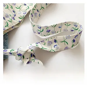 Detail of floral print satin shoulder strap with decorative knot on cream tote bag