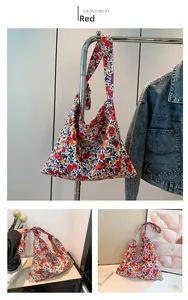 Detail view of red floral fabric tote bag with wide shoulder strap in a rustic style