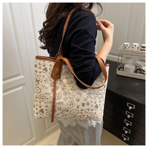 Detail of a straw tote bag with heart patterns and brown PU shoulder strap on a model